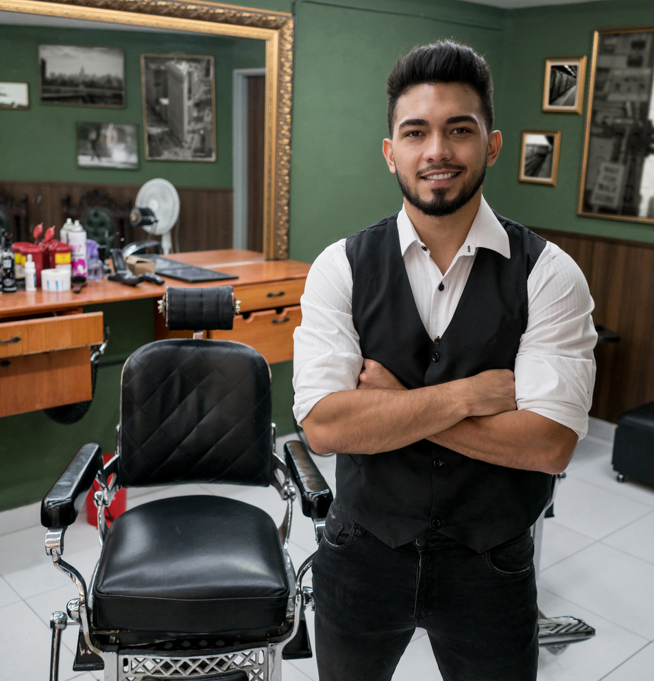 Business owner of a barber shop looking at camera smiling with arms crossed